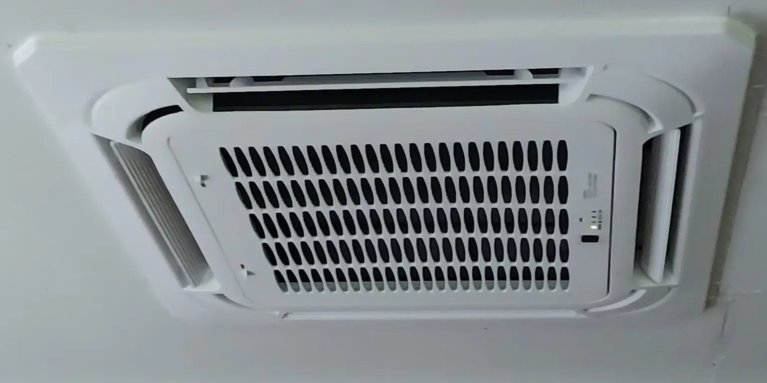 A white air conditioner with black vents on the outside.